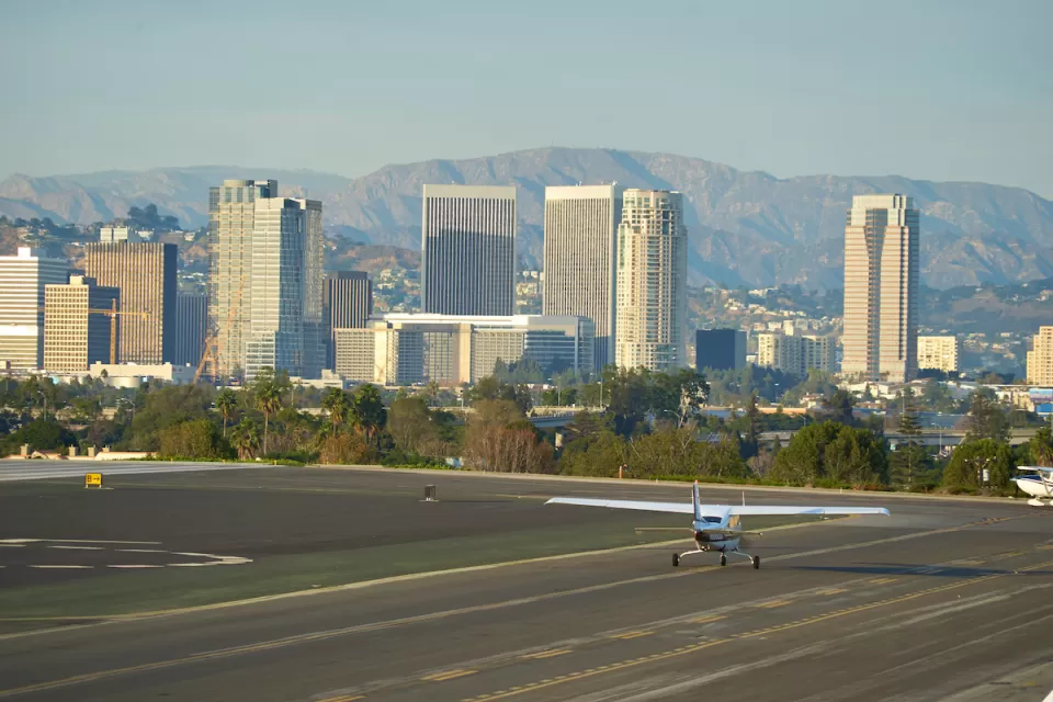 Small plane on runway at Santa Monica airport with high-rise buildings in background.